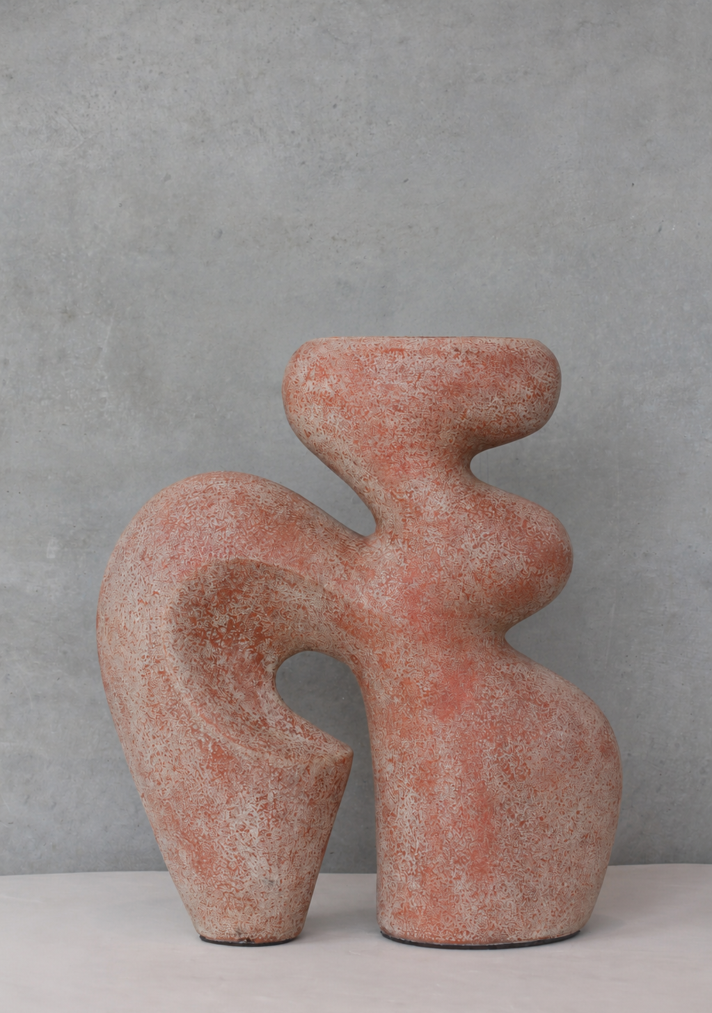 An abstract sculptural ceramic vase with a textured terracotta finish