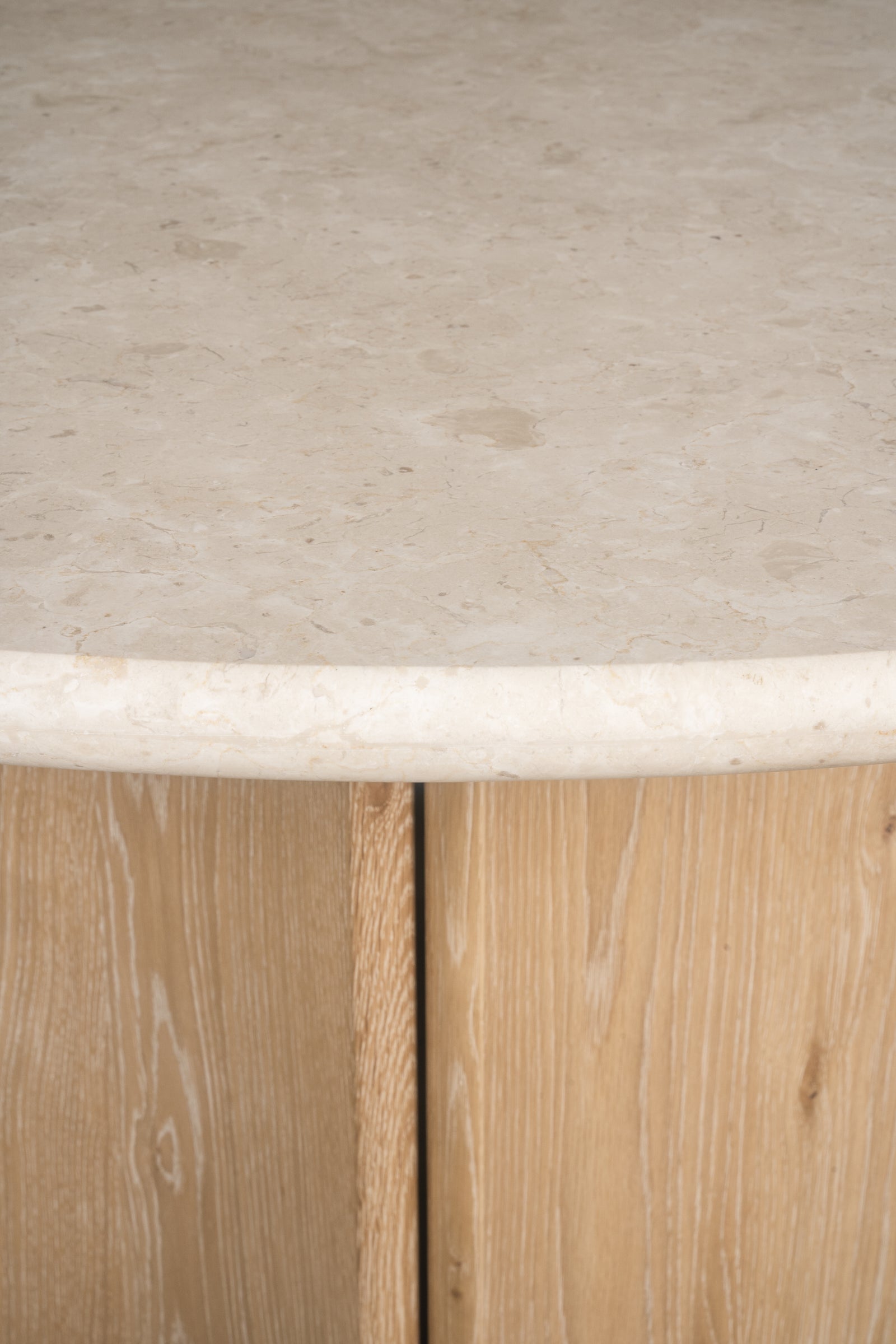 Close-up of the Cesena | Dining Table, showcasing its smooth marble top and sturdy wooden legs with a natural grain pattern.