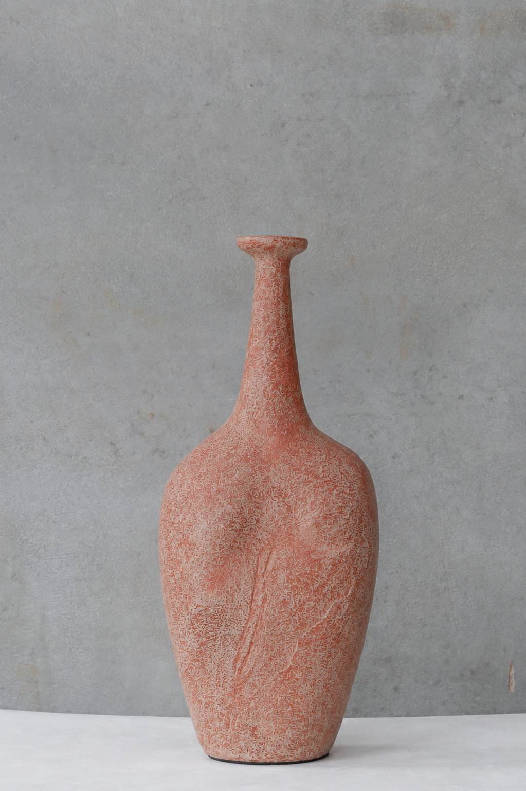 A textured terracotta fiber cement vase with a narrow neck and bulbous body